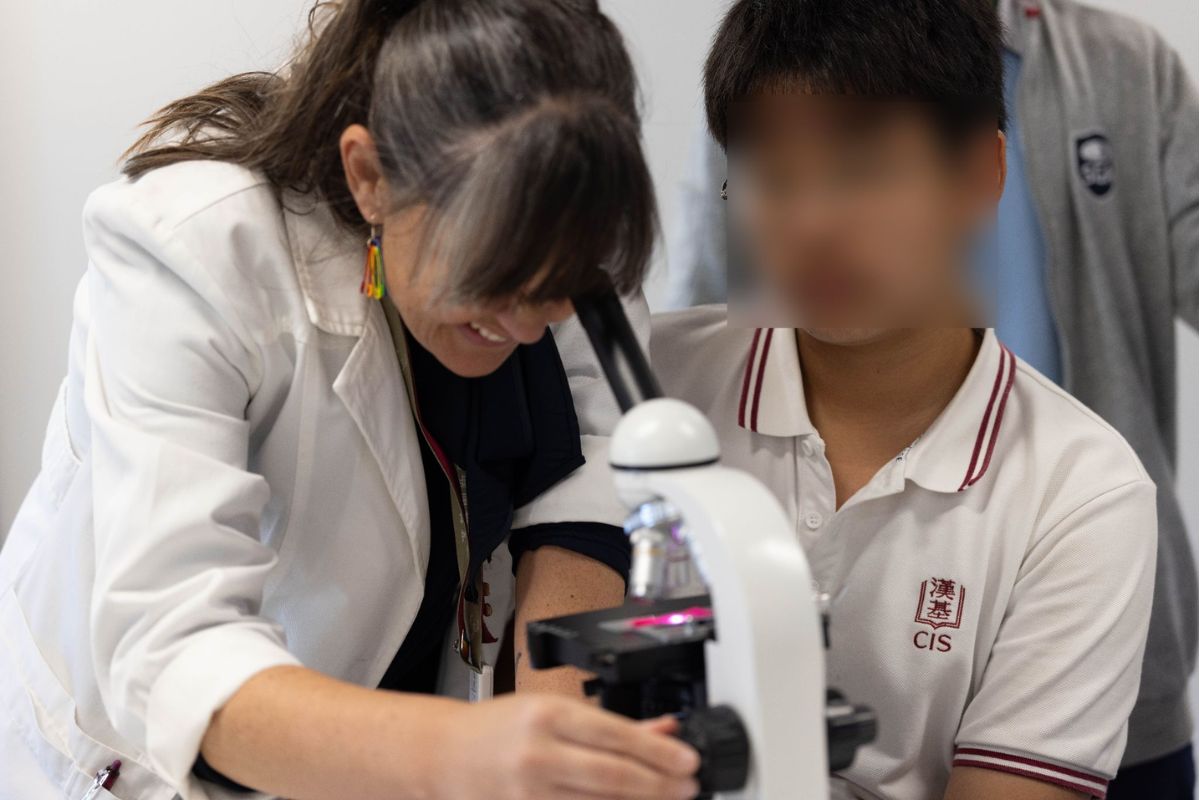 Teacher supporting a child in a science lab, encouraging inquiry-based learning through a practical experiment